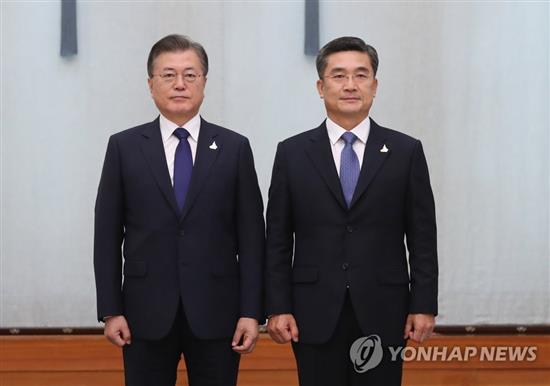 9月18日，在青瓦台，韩国总统文在寅（左）向新任防长徐旭颁发任命书后合影留念。